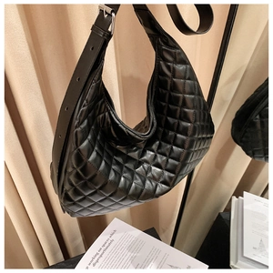 Detail of black quilted leather shoulder bag with adjustable silver metal buckle