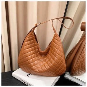 Detailed view of caramel quilted leather hobo bag on a fashion book background
