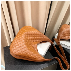 Detail of a brown quilted leather hobo bag featuring silver hardware and adjustable strap
