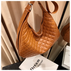 Detail of caramel quilted crossbody bag with adjustable strap and diamond stitching texture