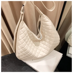 Detail of off-white quilted shoulder bag with diamond pattern on a minimalist background