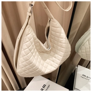 Detail of cream quilted crescent bag featuring adjustable strap and silver hardware