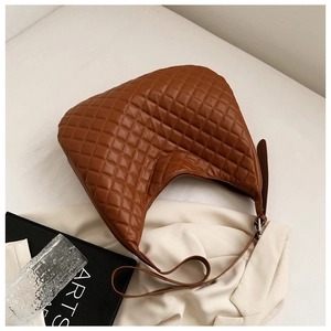 Detail of a brown quilted hobo bag with a crescent shape and adjustable leather strap