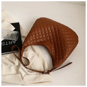 Top view of brown quilted hobo shoulder bag with silver buckle on white fabric background