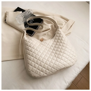 Chic quilted beige hobo bag displayed on fabric with elegant minimalist lifestyle props