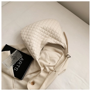 Close-up of cream quilted crescent shoulder bag with elegant diamond stitching details