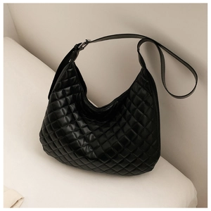Detail of glossy black quilted hobo bag featuring wide adjustable strap and silver metal buckle