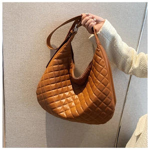 Close-up of brown quilted hobo bag with large diamond stitching and adjustable strap