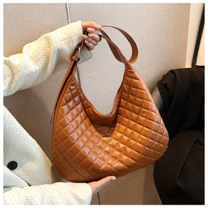 Detail of caramel brown quilted hobo bag featuring premium diamond stitching and a wide strap