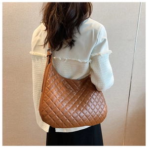 Detail view of a brown quilted leather hobo bag worn by a model on a light background
