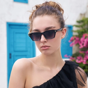 Détail de lunettes de soleil rectangulaires noires avec touches dorées portées par un mannequin