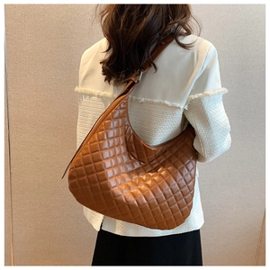 Rear view of model wearing a large brown quilted hobo bag with classic diamond stitching