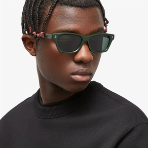 Gros plan de lunettes de soleil carrées vert foncé avec verres gris sur modèle