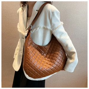 Quilted brown leather hobo bag for women worn by a model in a minimal interior setting