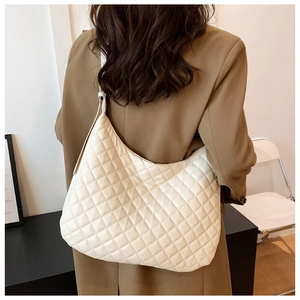 Detailed view of beige quilted hobo bag featuring soft diamond texture on model