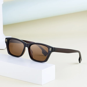 Lunettes de soleil œil de chat noires avec verres ambrés sur support géométrique