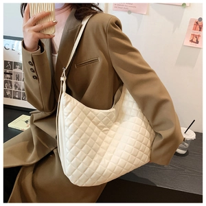 Close-up of white quilted tote bag on model showing large capacity and diamond stitching