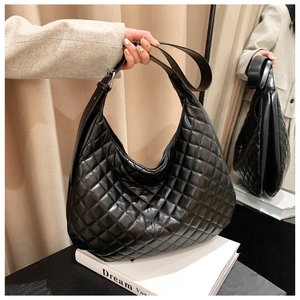 Detail of black quilted hobo bag with adjustable strap and silver buckle shown in mirror