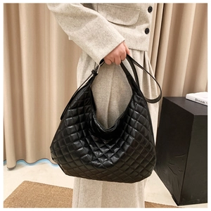 Close-up of black quilted hobo bag with glossy finish and adjustable shoulder strap