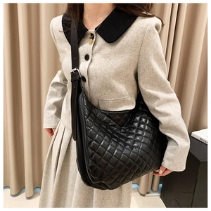 Detail of black quilted hobo bag with adjustable strap worn on casual wool blazer outfit