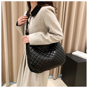 Side view of large black quilted tote bag with adjustable shoulder strap on female model