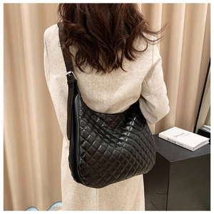 Detail of adjustable leather strap with silver buckle on black quilted hobo bag