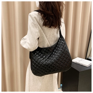 Close-up of black quilted leather crescent tote bag with elegant pleated side details