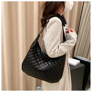 Side view of black quilted tote bag with diamond stitching on a female model