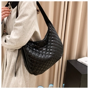 Close-up of black quilted rhombus crossbody bag with adjustable wide shoulder strap