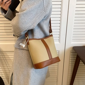 Retro bucket shoulder bag with beige lychee texture and brown leather trim on a model