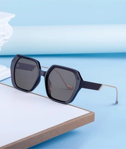 Détail de lunettes de soleil carrées avec monture noire et branche en métal doré chic