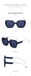 Détail des lunettes de soleil carrées noires avec branches dorées ondulées
