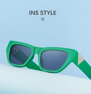 Detail of green cat-eye sunglasses featuring metallic triangle hinges and wide frames