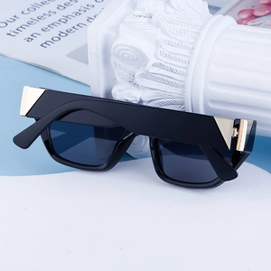 Detail of black cat eye sunglasses featuring gold triangular accents on a stone pedestal