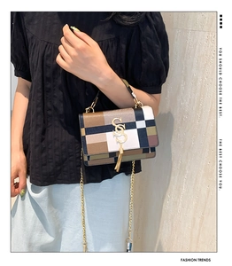 Detailed view of color-block flap bag with golden S-buckle and metallic tassels