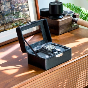 Close-up of black leather watch storage box with transparent window and metal clasp