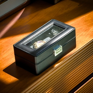 Detail of a 12-slot black PU leather watch box with clear glass lid and silver metal clasp
