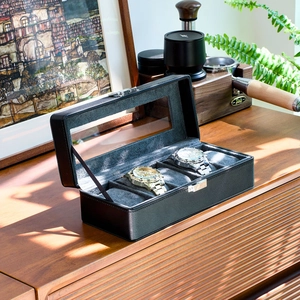 Three-slot black PU leather watch box with glass window and metal clasp on wood surface