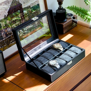 Detail of 10-slot black leather watch box with glass window on a wooden table