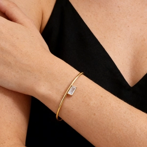 Detailed view of gold plated minimalist bangle with rectangular zircon on wrist