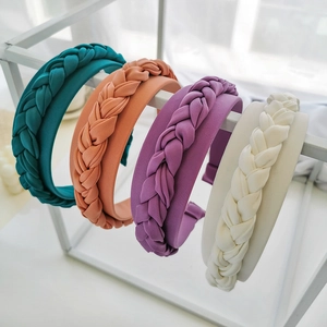 Detail of four wide braided headbands in blue, orange, purple, and white matte fabric