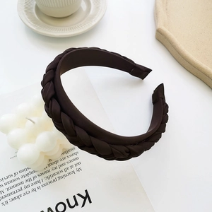 Detail of a dark brown braided headband with twisted texture on a minimalist background