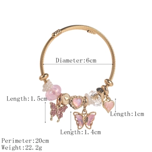 Gold-tone twisted bangle featuring butterfly and heart charms with pink beads and pearls