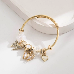 Golden beaded bangle with crystal butterflies and heart charms on a white display