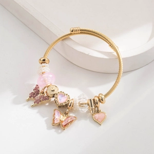 Detailed shot of golden twist bangle featuring pink crystal butterfly and heart charms