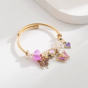 Macro view of gold wire cable bracelet with heart charms and purple butterfly accents