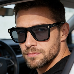 Close-up of black square frame sunglasses with golden arrow details on a male model