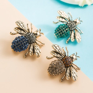 Detailed view of three vintage gold bee brooches with blue green and amber rhinestones