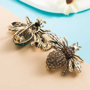 Detail view of vintage alloy bee brooches with amber and emerald rhinestones