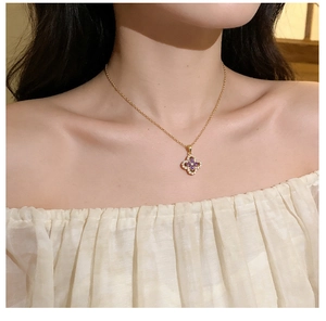 Detail of four-leaf clover pendant with purple stones and diamonds on gold chain